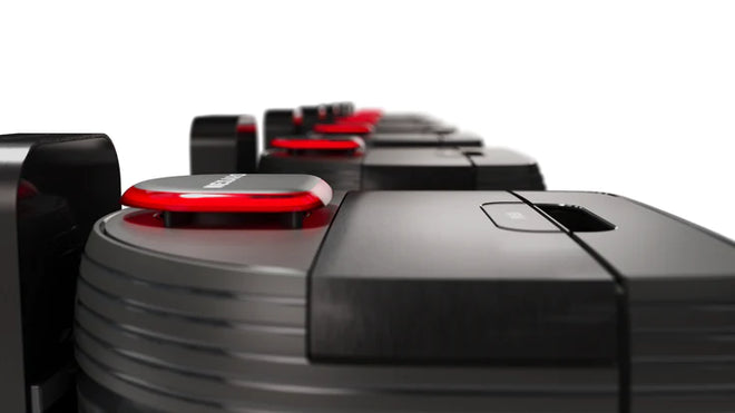 Close-up of several black and red robotic vacuum cleaners lined up in a row against a white background.
