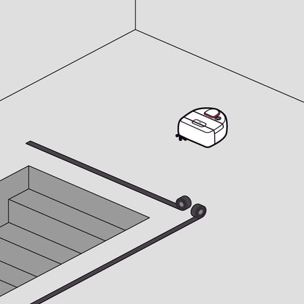 A robotic vacuum cleaner approaches stairs, stopped by a safety barrier on the floor.
