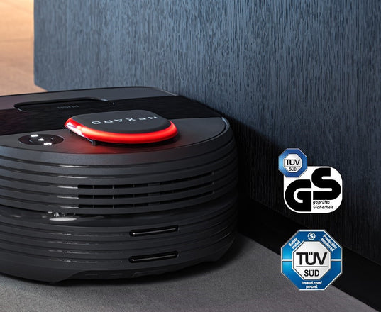 A robot vacuum cleaner near a wall with TUV SUD and GS certification logos displayed beside it.
