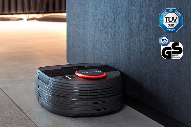 A robotic vacuum cleans along a wall, with TÜV SÜD and GS certification logos shown in the corner.