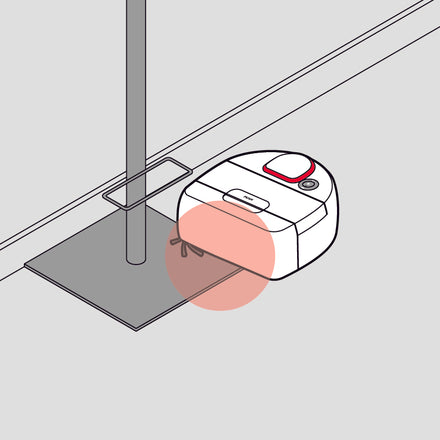 A robot vacuum cleaning around a floor lamp with a red highlighted area beneath its brush.