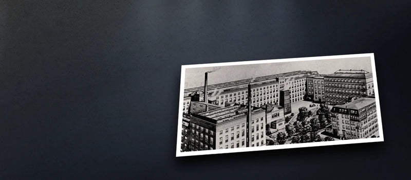 A black-and-white drawing of an old industrial building complex on a dark background.