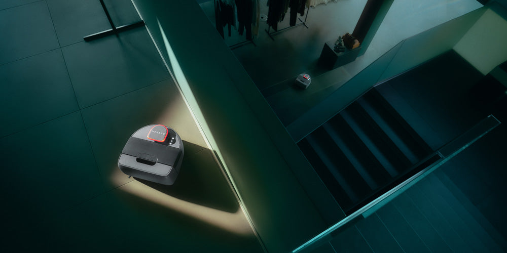 A robot vacuum cleans a modern, dimly lit home near stairs and a closet.