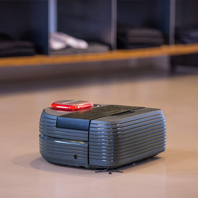 A robotic vacuum cleaner moves across a smooth floor in a modern indoor space.